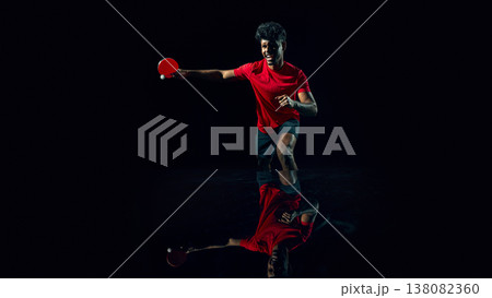 Table tennis player hitting fast ball in dark studio with reflection surface Table tennis player hitting fast ball in dark studio with reflection surface 138082360