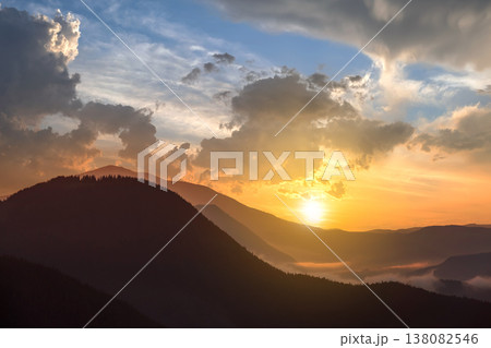 Sunset landscape of high mountain peaks and foggy valley under vibrant colorful evening sky. 138082546