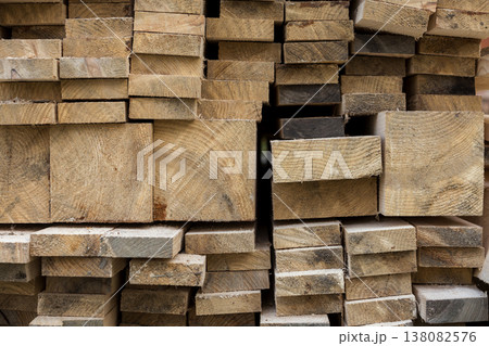 Stack of natural brown uneven rough wooden boards different size, cross-sectional view. Industrial timber for carpentry, building, repairing and furniture, lumber material for construction. Stack of natural brown uneven rough wooden boards different size, cross-sectional view. Industrial timber for carpentry, building, repairing and furniture, lumber material for construction. 138082576