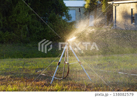 Sprinkler watering lawn grass during dry season 138082579