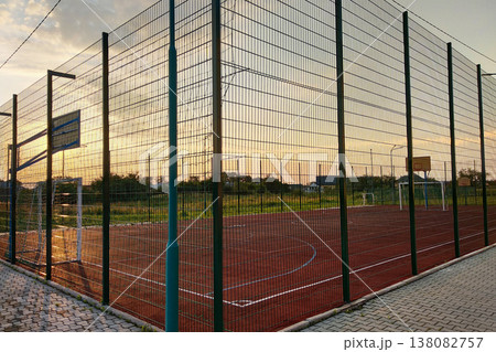 Outdoors mini football and basketball court with ball gate and basket surrounded with high protective fence. Outdoors mini football and basketball court with ball gate and basket surrounded with high protective fence. 138082757