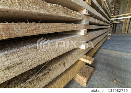 Neatly piled long stack of wooden boards inside attic room under construction. Neatly piled long stack of wooden boards inside attic room under construction. 138082786