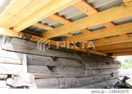 Wooden beams framework with metal angle brackets supporting corrugated roof panels, construction detail from below 138082870