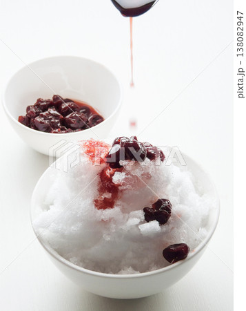 Shaved ice Kakigori granita berry dessert for summer made of ice with juice sauce in bowl on table. Shaved ice Kakigori granita berry dessert for summer made of ice with juice sauce in bowl on table. 138082947
