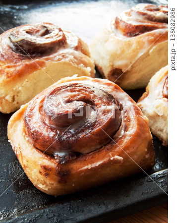 Freshly baked homemade cinnamon rolls with sweet cream cheese lying on oven pan. 138082986