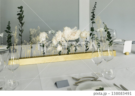 Long minimalist centerpiece with eucalyptus and white flowers hydrangea on table 138083491