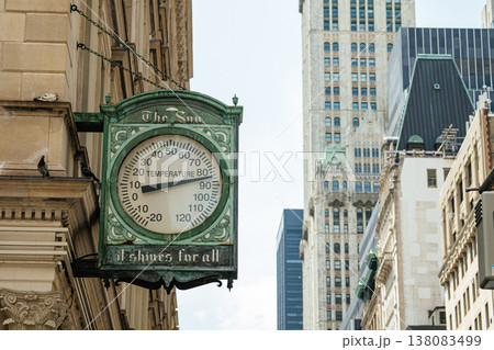 A vintage green Sun clock thermometer sign hangs on a historic building facade in Manhattan, New York City. Skyscrapers rise in the background highlighting the contrast of classic and modern A vintage green Sun clock thermometer sign hangs on a historic building facade in Manhattan, New York City. Skyscrapers rise in the background highlighting the contrast of classic and modern 138083499