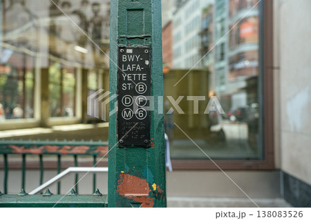 A Broadway Lafayette Street subway sign displays the B, D, F, M, and 6 train lines in New York City. The green station entrance and urban background emphasize the city transportation system. A Broadway Lafayette Street subway sign displays the B, D, F, M, and 6 train lines in New York City. The green station entrance and urban background emphasize the city transportation system. 138083526