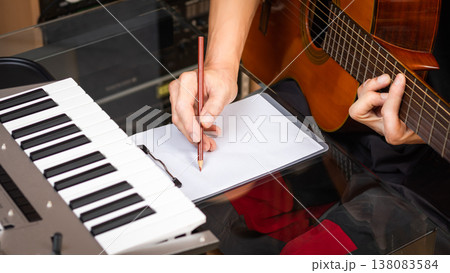 male musician writing a hit song by acoustic guitar in home studio. songwriting concept male musician writing a hit song by acoustic guitar in home studio. songwriting concept 138083584