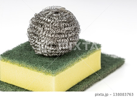 Close-Up of Stainless Steel Wire Wool Scrubber Ball Balanced on Top of a Green and Yellow Dual-Layer Kitchen Cleaning Sponge Against White Background Close-Up of Stainless Steel Wire Wool Scrubber Ball Balanced on Top of a Green and Yellow Dual-Layer Kitchen Cleaning Sponge Against White Background 138083763
