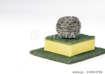 Steel Wool Scrubber Ball Resting on a Yellow Foam Kitchen Sponge Layered over a Green Abrasive Scouring Pad, Isolated on Clean White Background for Household Cleaning Concept Steel Wool Scrubber Ball Resting on a Yellow Foam Kitchen Sponge Layered over a Green Abrasive Scouring Pad, Isolated on Clean White Background for Household Cleaning Concept 138083766