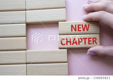 New Chapter symbol. Concept word New Chapter on wooden blocks. Businessman hand. Beautiful pink background. Business and New Chapter concept. Copy space New Chapter symbol. Concept word New Chapter on wooden blocks. Businessman hand. Beautiful pink background. Business and New Chapter concept. Copy space 138083821