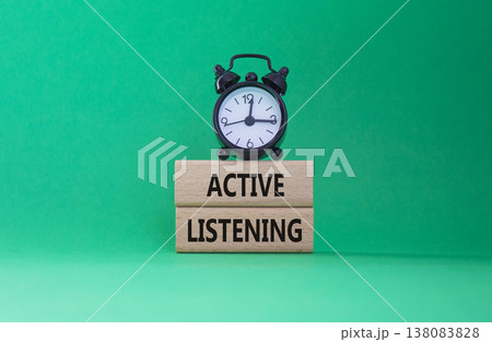Listen actively symbol. Wooden blocks with words Listen actively. Beautiful green background with alarm clock. Business and Active listening concept. Copy space. 138083828