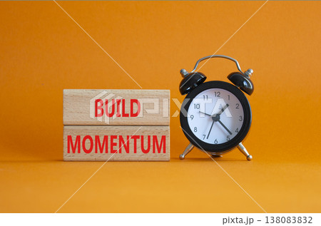Build momentum symbol. Wooden blocks with words Build momentum. Beautiful orange background with alarm clock. Business and Build momentum concept. Copy space. Build momentum symbol. Wooden blocks with words Build momentum. Beautiful orange background with alarm clock. Business and Build momentum concept. Copy space. 138083832