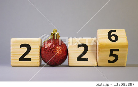 2026 New Year symbol. Businessman turns wooden cube and changes Year 2025 to 2026. Beautiful grey background with Christmas ball. Copy space. Business and 2026 happy new year concept 2026 New Year symbol. Businessman turns wooden cube and changes Year 2025 to 2026. Beautiful grey background with Christmas ball. Copy space. Business and 2026 happy new year concept 138083897