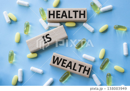 Health is Wealth symbol. Concept word Health is Wealth on wooden blocks. Beautiful blue background with pills. Medicine and Health is Wealth concept. Copy space Health is Wealth symbol. Concept word Health is Wealth on wooden blocks. Beautiful blue background with pills. Medicine and Health is Wealth concept. Copy space 138083949