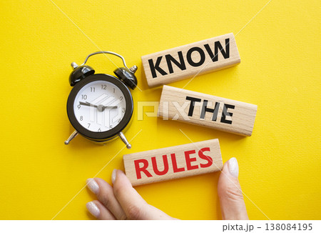 Know the rules symbol. Wooden blocks with words Know the rules. Businessman hand. Beautiful yellow background with alarm clock. Business and Know the rules concept. Copy space. Know the rules symbol. Wooden blocks with words Know the rules. Businessman hand. Beautiful yellow background with alarm clock. Business and Know the rules concept. Copy space. 138084195