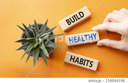 Healthy habits symbol. Concept word Build Healthy habits on wooden blocks. Doctor hand. Beautiful orange background with succulent plant. Healthy lifestyle and Healthy habits concept. Copy space Healthy habits symbol. Concept word Build Healthy habits on wooden blocks. Doctor hand. Beautiful orange background with succulent plant. Healthy lifestyle and Healthy habits concept. Copy space 138084198