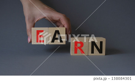 Earn symbol. Concept word Earn on wooden cubes. Businessman hand. Beautiful grey background. Business and Earn concept. Copy space. Earn symbol. Concept word Earn on wooden cubes. Businessman hand. Beautiful grey background. Business and Earn concept. Copy space. 138084301