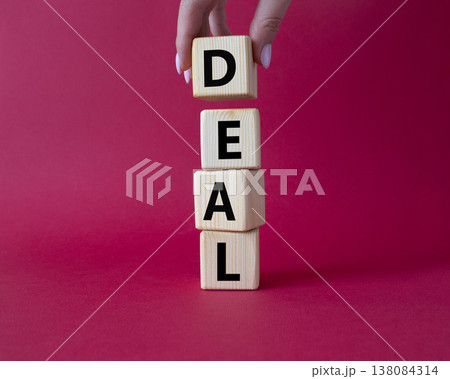 Deal symbol. Concept word Deal on wooden cubes. Businessman hand. Beautiful red background. Business and Deal concept. Copy space. Deal symbol. Concept word Deal on wooden cubes. Businessman hand. Beautiful red background. Business and Deal concept. Copy space. 138084314