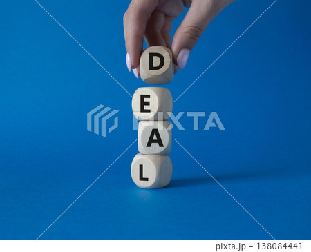 Deal symbol. Concept word Deal on wooden cubes. Businessman hand. Beautiful blue background. Business and Deal concept. Copy space. Deal symbol. Concept word Deal on wooden cubes. Businessman hand. Beautiful blue background. Business and Deal concept. Copy space. 138084441