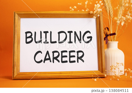 Building Career symbol. Concept words Building Career on beautiful wooden picture frame. Beautiful orange background with flower vase. Business and Building Career concept. Copy space. Building Career symbol. Concept words Building Career on beautiful wooden picture frame. Beautiful orange background with flower vase. Business and Building Career concept. Copy space. 138084511