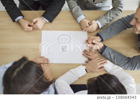 Team of people developing new creative business idea at table with lightbulb drawing Team of people developing new creative business idea at table with lightbulb drawing 138084543