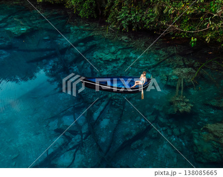Woman floating on boat in lake with blue fresh water in Sulawesi, Indonesia. Aerial view 138085665