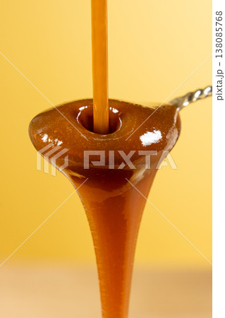 Sweet caramel sauce dripping from spoon, liquid caramel close-up. 138085768