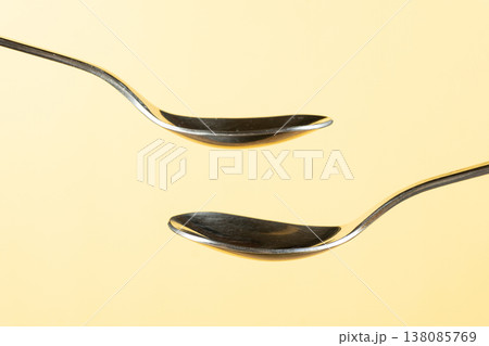 Two empty spoons on yellow background for design. 138085769