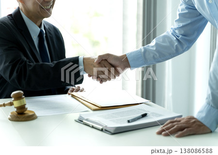 Business people in an law firm office establishing a corporate agreement with a handshake Business people in an law firm office establishing a corporate agreement with a handshake 138086588