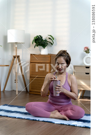 Smile woman in yoga dress sit on yoga mate Drink water to relax Smile woman in yoga dress sit on yoga mate Drink water to relax 138086591