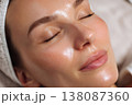 close-up portrait of woman with radiant skin after gold facial treatment, beautician slightly 138087360