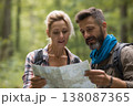 attractive middle-aged woman in her 30s checking trail map with companion during hike, teamwork 138087365