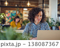 attractive middle-aged woman in her 30s working on laptop with colleague in coworking space, 138087367