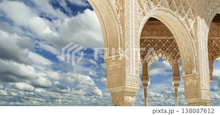 Arches in Islamic (Moorish) style (against the background of a beautiful sky with clouds) in Alhambra, Granada, Spain Arches in Islamic (Moorish) style (against the background of a beautiful sky with clouds) in Alhambra, Granada, Spain 138087612