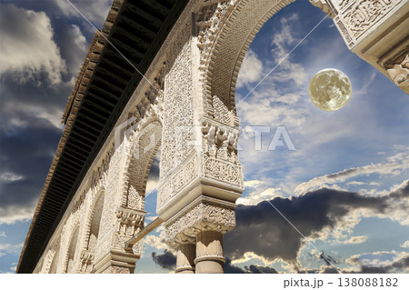 Arches in Islamic (Moorish) style (against the background of a beautiful evening sky with clouds with the super moon) in Alhambra, Granada, Spain Arches in Islamic (Moorish) style (against the background of a beautiful evening sky with clouds with the super moon) in Alhambra, Granada, Spain 138088182