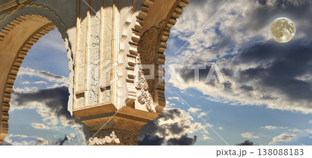 Arches in Islamic (Moorish) style (against the background of a beautiful evening sky with clouds with the super moon) in Alhambra, Granada, Spain Arches in Islamic (Moorish) style (against the background of a beautiful evening sky with clouds with the super moon) in Alhambra, Granada, Spain 138088183