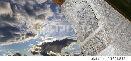 Arches in Islamic (Moorish) style (against the background of a beautiful evening sky with clouds with the super moon) in Alhambra, Granada, Spain Arches in Islamic (Moorish) style (against the background of a beautiful evening sky with clouds with the super moon) in Alhambra, Granada, Spain 138088184