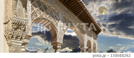 Arches in Islamic (Moorish) style (against the background of a beautiful evening sky with clouds with the super moon) in Alhambra, Granada, Spain 138088262
