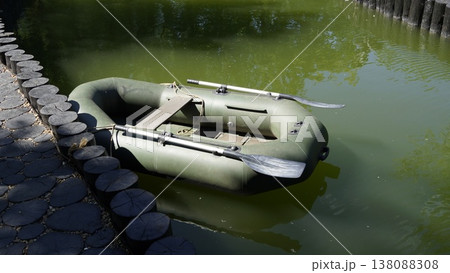 A dark green two-seater inflatable boat with oars for fishing and water recreation 138088308