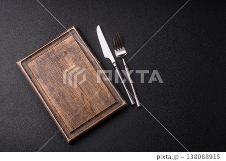 An empty wooden cutting board with cutlery on a kitchen counter. A wooden cutting board An empty wooden cutting board with cutlery on a kitchen counter. A wooden cutting board 138088915