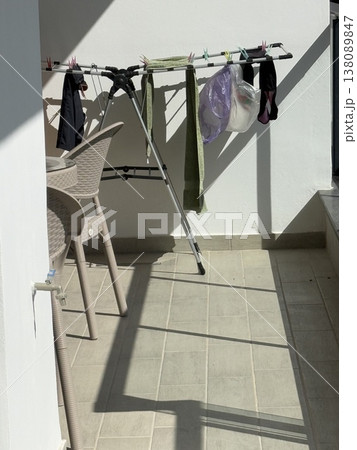 Laundry drying in sunlight on a balcony with shadows cast on the wall background Laundry drying in sunlight on a balcony with shadows cast on the wall background 138089847