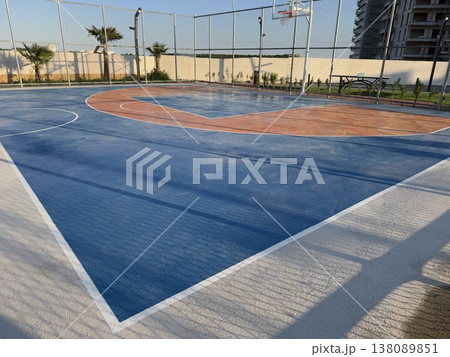 Outdoor basketball court with blue and orange markings under clear sky, suitable as sports background 138089851