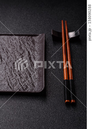 An empty ceramic square black plate with chopsticks for Asian food. An empty square plate An empty ceramic square black plate with chopsticks for Asian food. An empty square plate 138090288