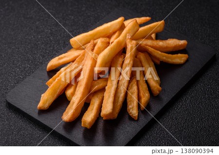 French fries, a salty, crispy, homemade snack with spices. French fries on a black background French fries, a salty, crispy, homemade snack with spices. French fries on a black background 138090394