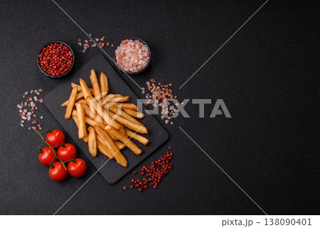 French fries, a salty, crispy, homemade snack with spices. French fries on a black background French fries, a salty, crispy, homemade snack with spices. French fries on a black background 138090401