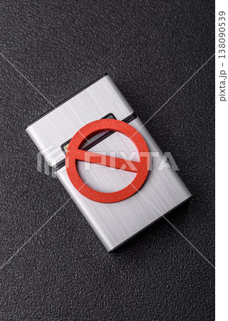 A metal cigarette box with a no smoking sign depicts a harmful habit. A cigarette box A metal cigarette box with a no smoking sign depicts a harmful habit. A cigarette box 138090539