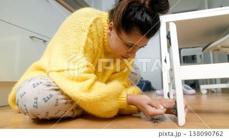 Lady Fixing Furniture. Female Fixing Table Support Beneath With Careful Attention To Detail And Precision Lady Fixing Furniture. Female Fixing Table Support Beneath With Careful Attention To Detail And Precision 138090762