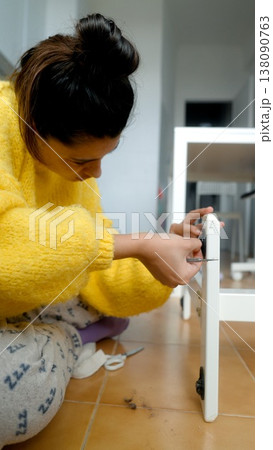 Woman Installing Cabinet In Kitchen. Female Worker Adjusting Cabinet Foot Near Kitchen Appliances Indoors 138090763